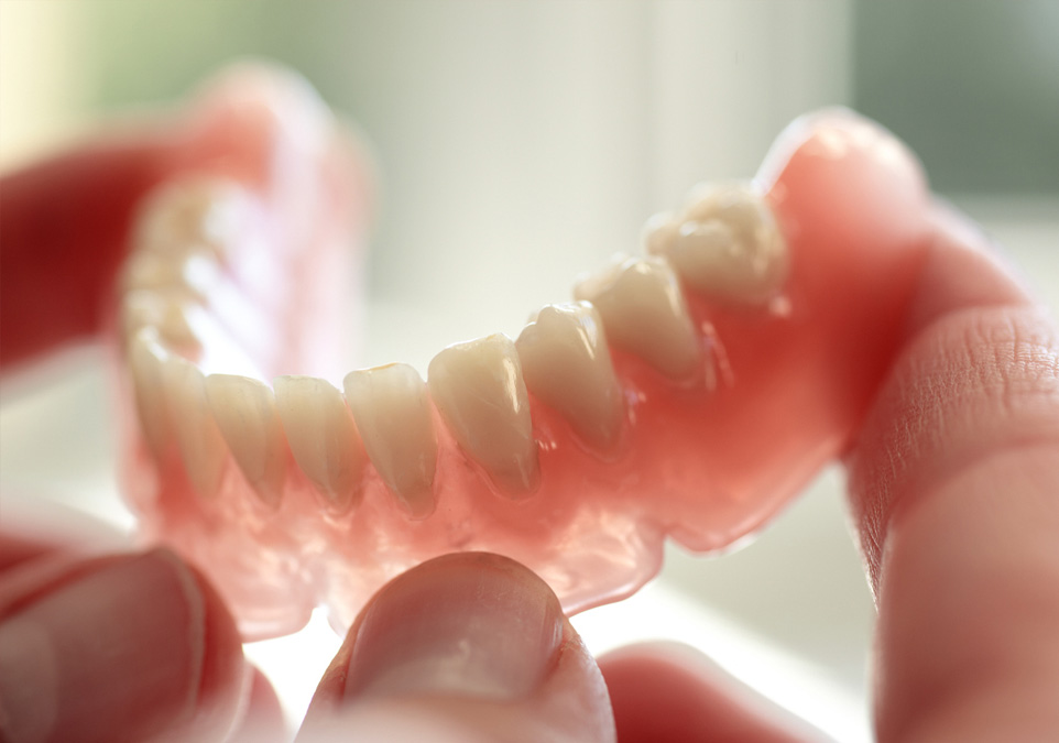 A person holding dentures closeup pic